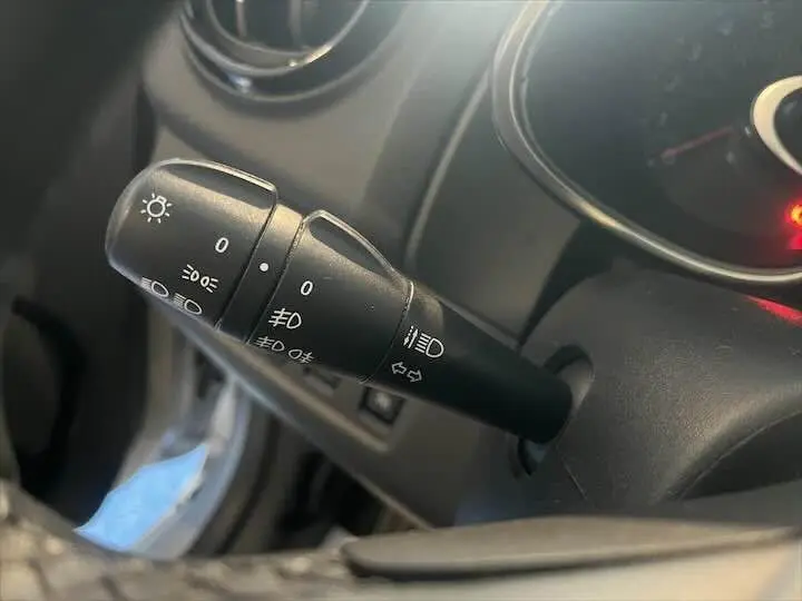 Gros plan sur la commande des feux à gauche du volant dans l'habitacle d'une Renault Clio gris argent 2019.