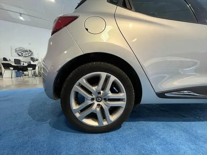 Gros plan sur la roue arrière gauche d'une Renault Clio IV gris argent, avec la trappe à carburant visible au-dessus.