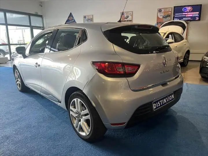 Renault Clio IV gris argent vue 3/4 arrière droit en showroom avec jantes alliage et plaque Distinxion.