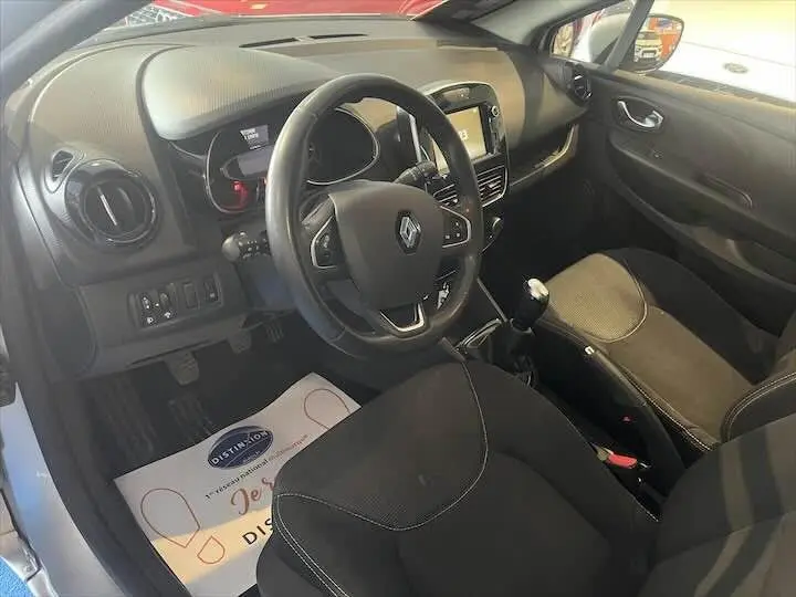 Intérieur noir de Renault Clio IV essence 2019, vue côté conducteur avec volant, tableau de bord et levier de vitesses manuel.