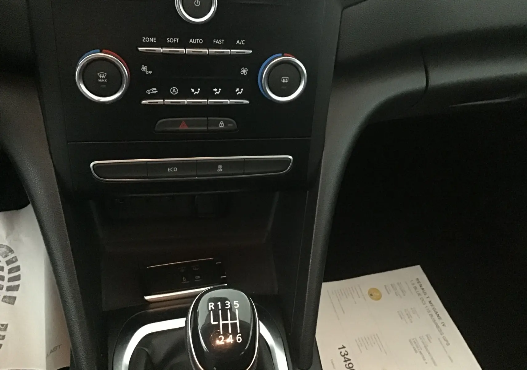 Console centrale de Renault Megane IV Berline blanche 2019, vue sur levier de vitesse manuel et commandes climatisation.