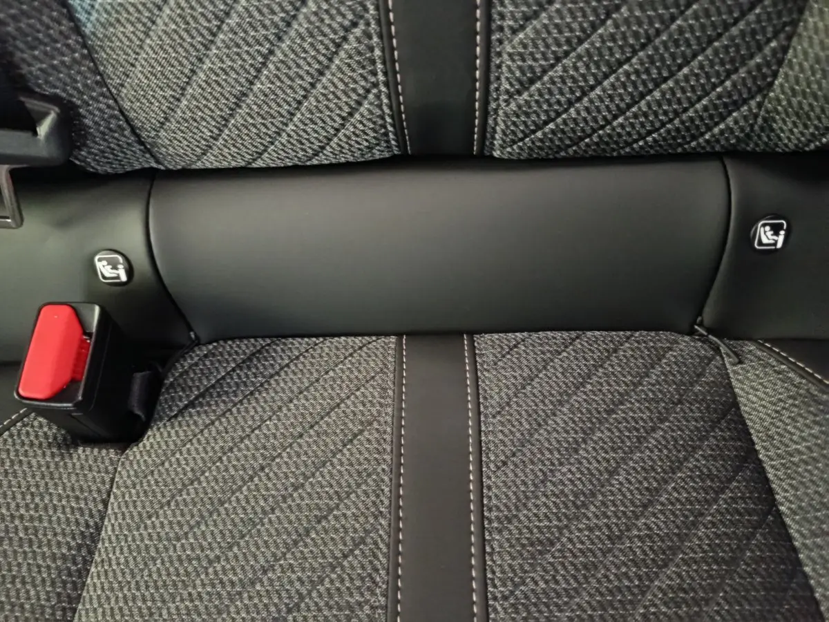 Gros plan sur la banquette arrière gris foncé à motifs avec ceinture rouge et fixations Isofix visibles.