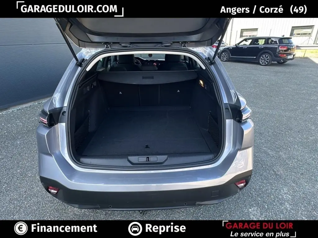 Coffre ouvert vu de l’arrière d’une Peugeot 308 gris clair, montrant un espace de chargement spacieux et propre.