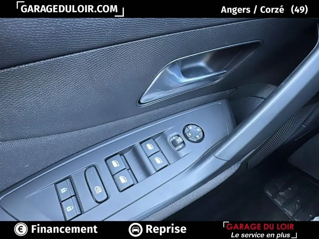 Détail de la porte côté conducteur de la Peugeot 308 gris clair 2023 avec commandes électriques des vitres et verrouillage.
