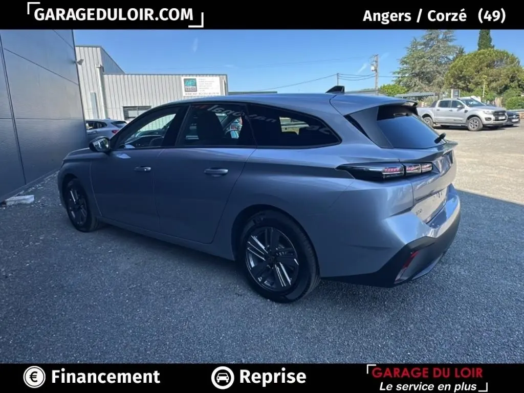 Vue 3/4 arrière droite d'une Peugeot 308 gris clair 2023 avec feux LED et carrosserie break élégante.