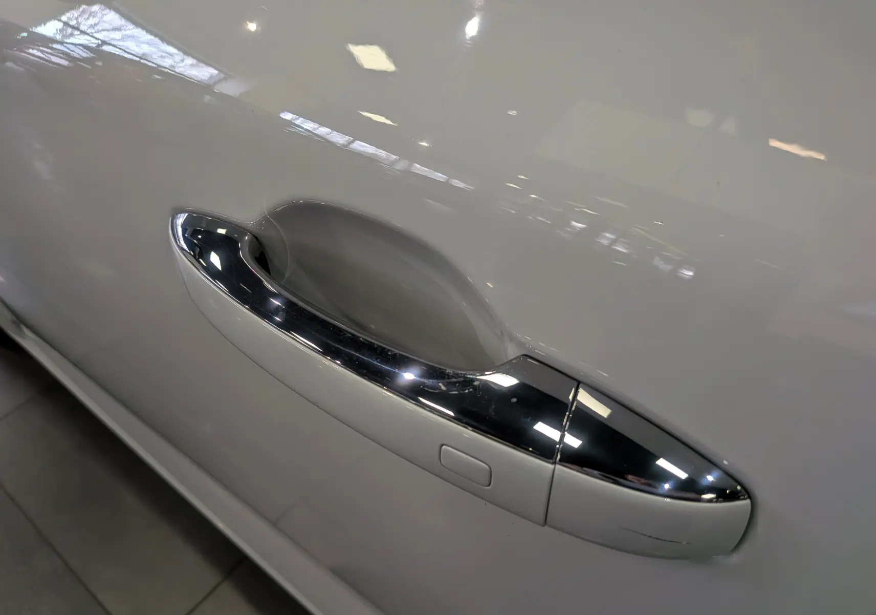 Poignée de porte chromée sur la portière côté gauche d'une Renault Mégane IV Berline Blanc Glacier 2021.