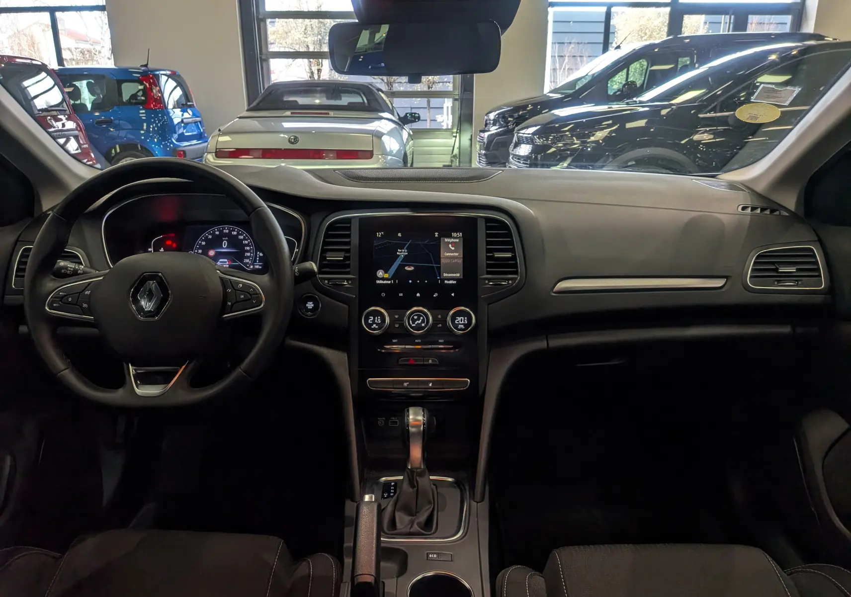 Vue intérieure frontale du tableau de bord de la Renault Mégane IV Berline Blue dCi blanc glacier avec écran tactile et volant multifonction.