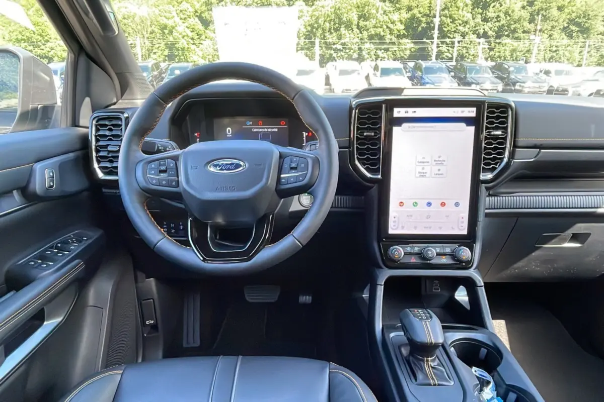 Vue intérieure frontale du Ford Ranger 2025 gris carbone, mettant en valeur le volant cuir multifonctions et l’écran tactile vertical.