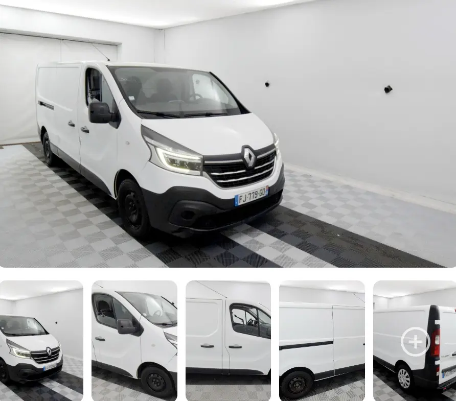 Renault Trafic Fourgon blanc vu en 3/4 avant droit dans un espace intérieur lumineux avec calandre noire.