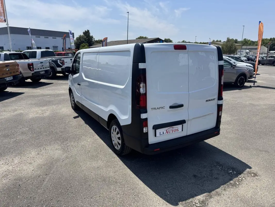 Vue 3/4 arrière droite d’un Renault Trafic Fourgon blanc 2019 avec portes arrière fermées sur parking.