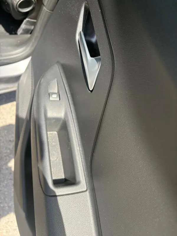 Gros plan sur la poignée intérieure et le bouton de verrouillage de la porte côté conducteur d’un Opel Mokka électrique gris.