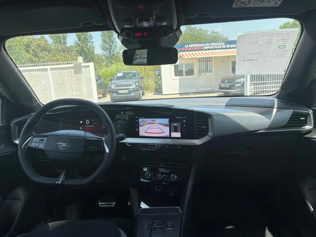 Vue intérieure avant de l'Opel Mokka électrique 2025, tableau de bord moderne avec écran tactile et volant multifonctions.