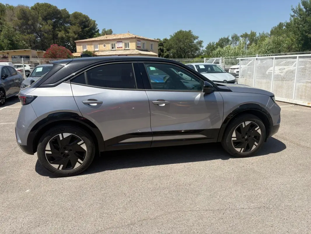 Opel Mokka électrique gris vue de profil côté gauche, avec vitres surteintées et jantes alliage 17 pouces.