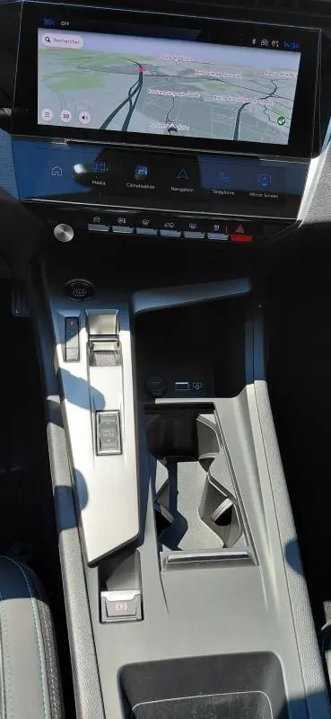 Vue plongeante sur la console centrale et l'écran tactile du Peugeot 308 SW Hybrid gris, avec levier de vitesse automatique et commandes digitales.