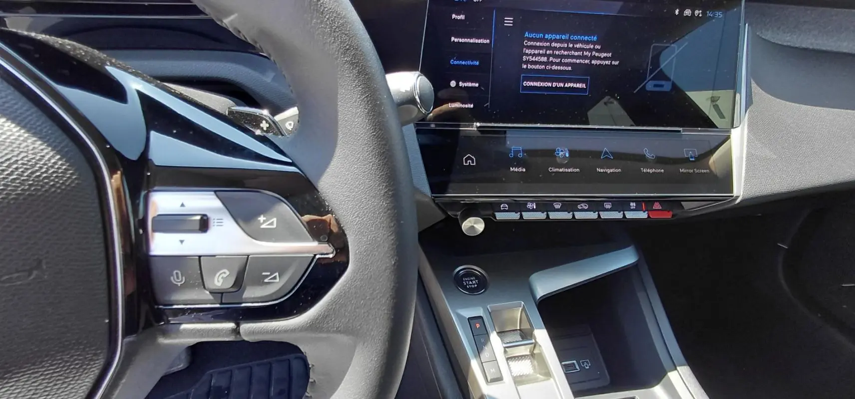 Vue rapprochée de l’intérieur de la Peugeot 308 SW Hybrid 145, montrant le volant, la console centrale et l’écran tactile.