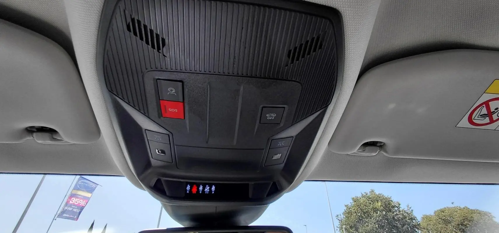 Vue intérieure en contre-plongée du plafonnier avec boutons SOS et commandes d’éclairage du Peugeot 308 SW gris.
