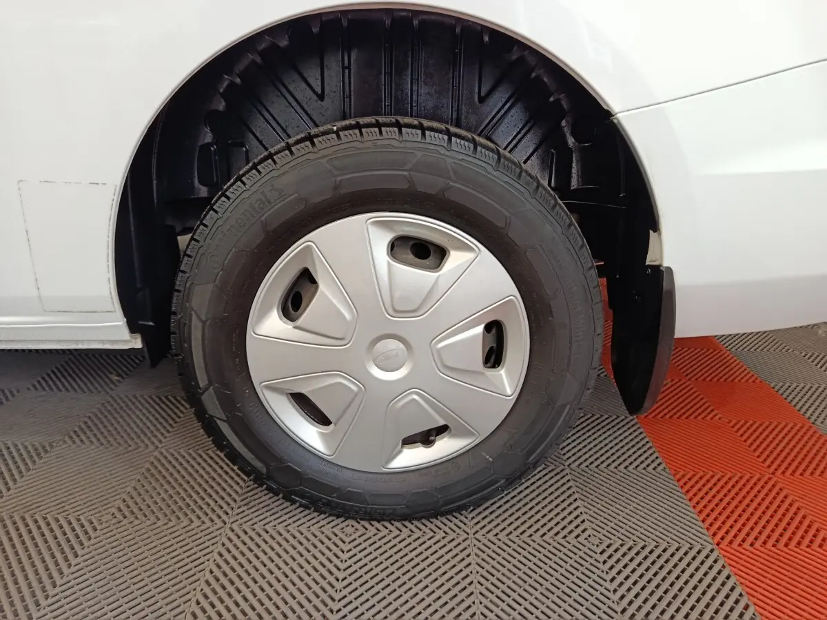 Gros plan sur la roue avant gauche d’un Ford Transit Custom blanc, avec enjoliveur argenté et pneu Continental.