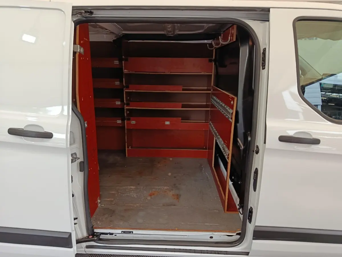 Vue intérieure côté droit du Ford Transit Custom blanc 2020 avec portes latérales ouvertes et aménagements de rangement rouges.