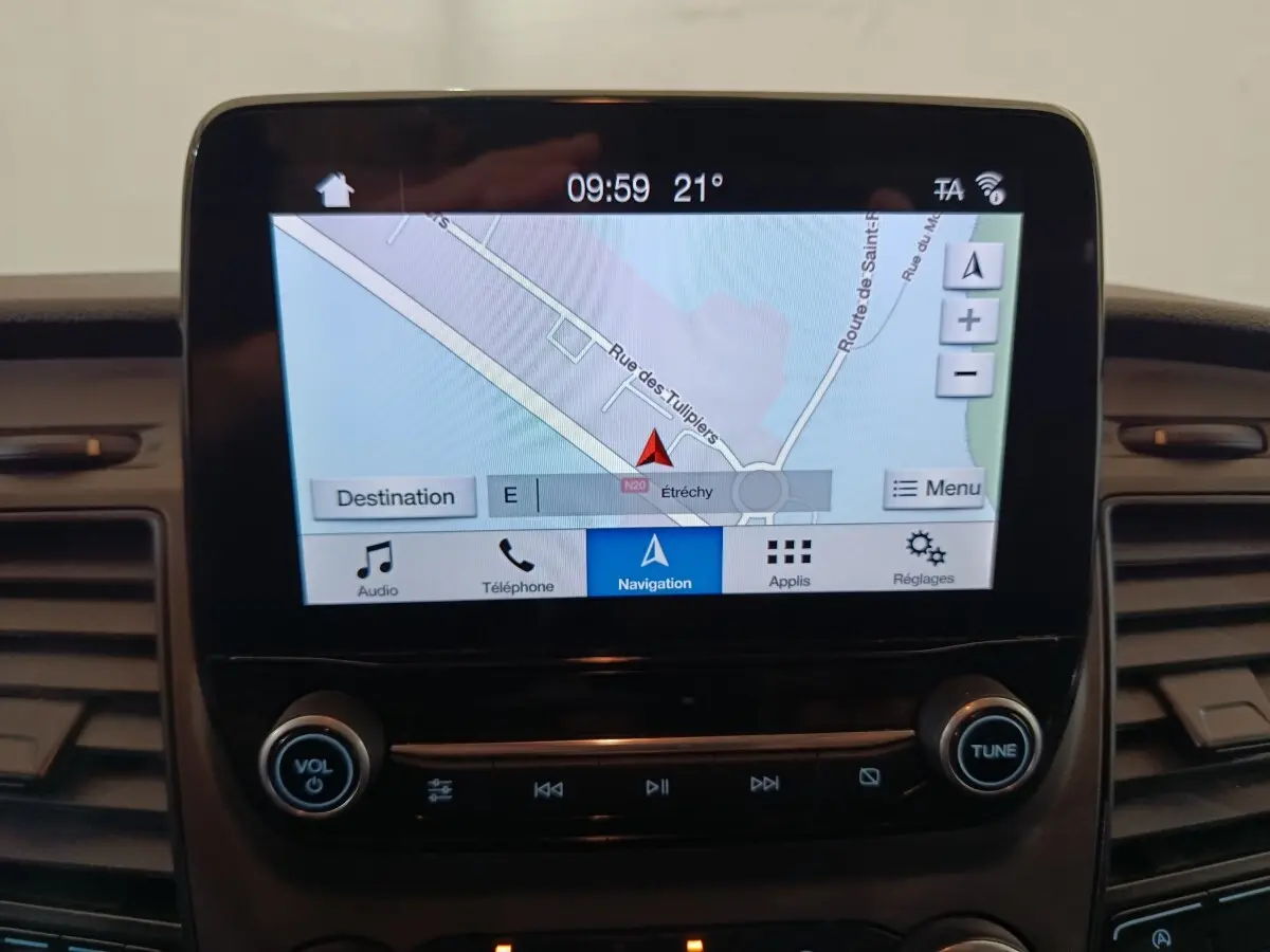 Écran tactile central du Ford Transit Custom blanc, affichant la navigation avec commandes audio en dessous.