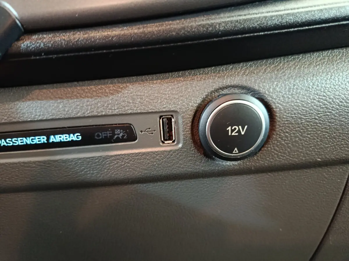 Détail intérieur du tableau de bord du Ford Transit Custom, prise 12V et port USB visibles sur plastique noir texturé.