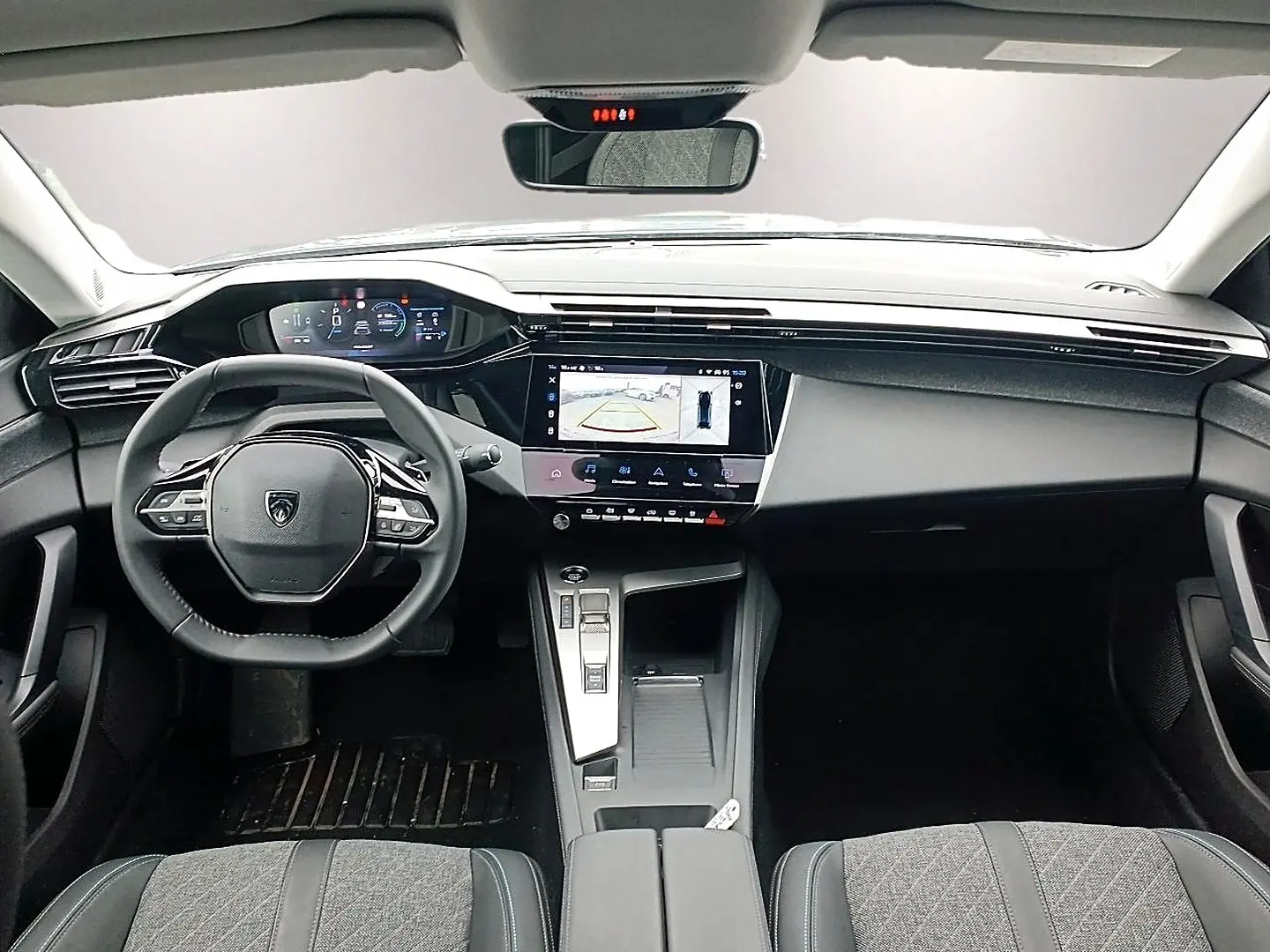 Vue intérieure avant de la Peugeot 408 Hybrid 145 allure 2024, tableau de bord noir avec écran tactile et volant multifonction.