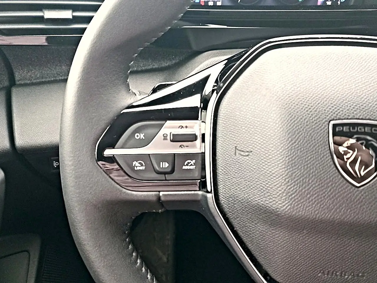 Gros plan sur le volant cuir noir multifonction de la Peugeot 408 Hybrid 145 allure, avec logo lion central.