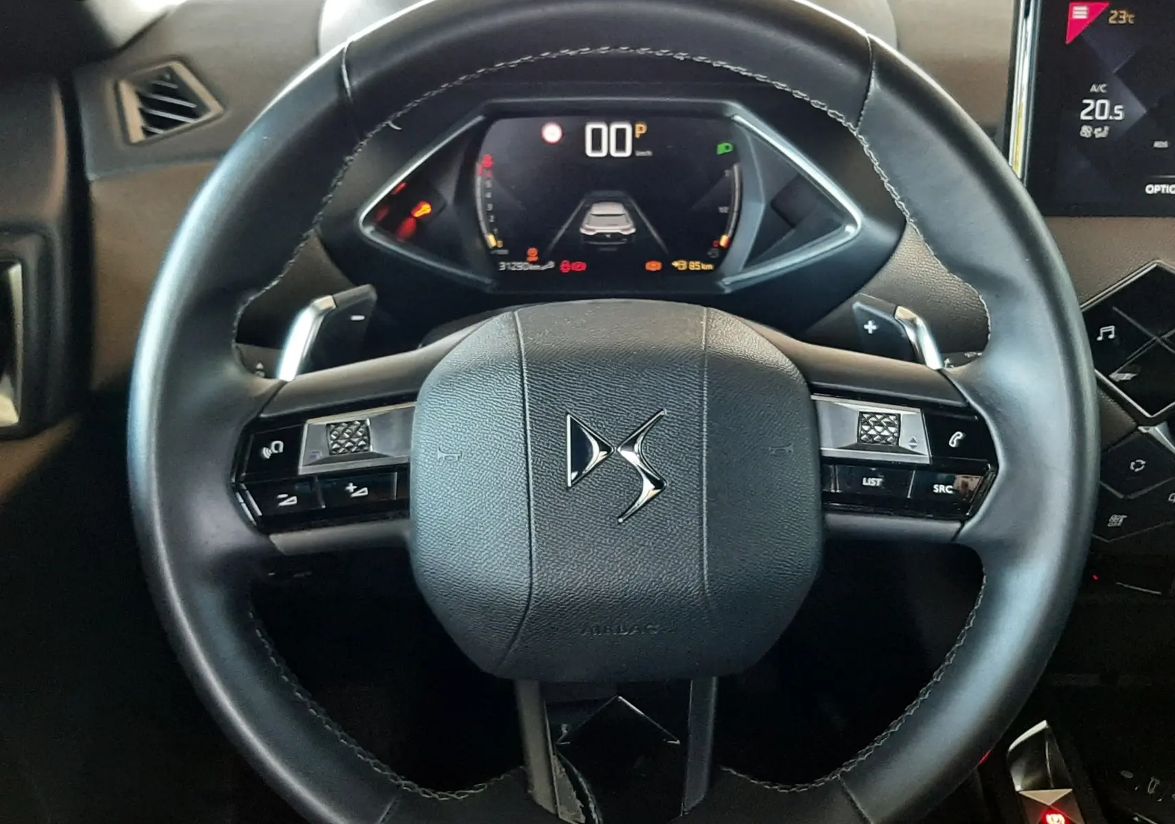 Vue rapprochée du volant DS en cuir noir du DS3 Crossback 2020 avec tableau de bord numérique et commandes intégrées.