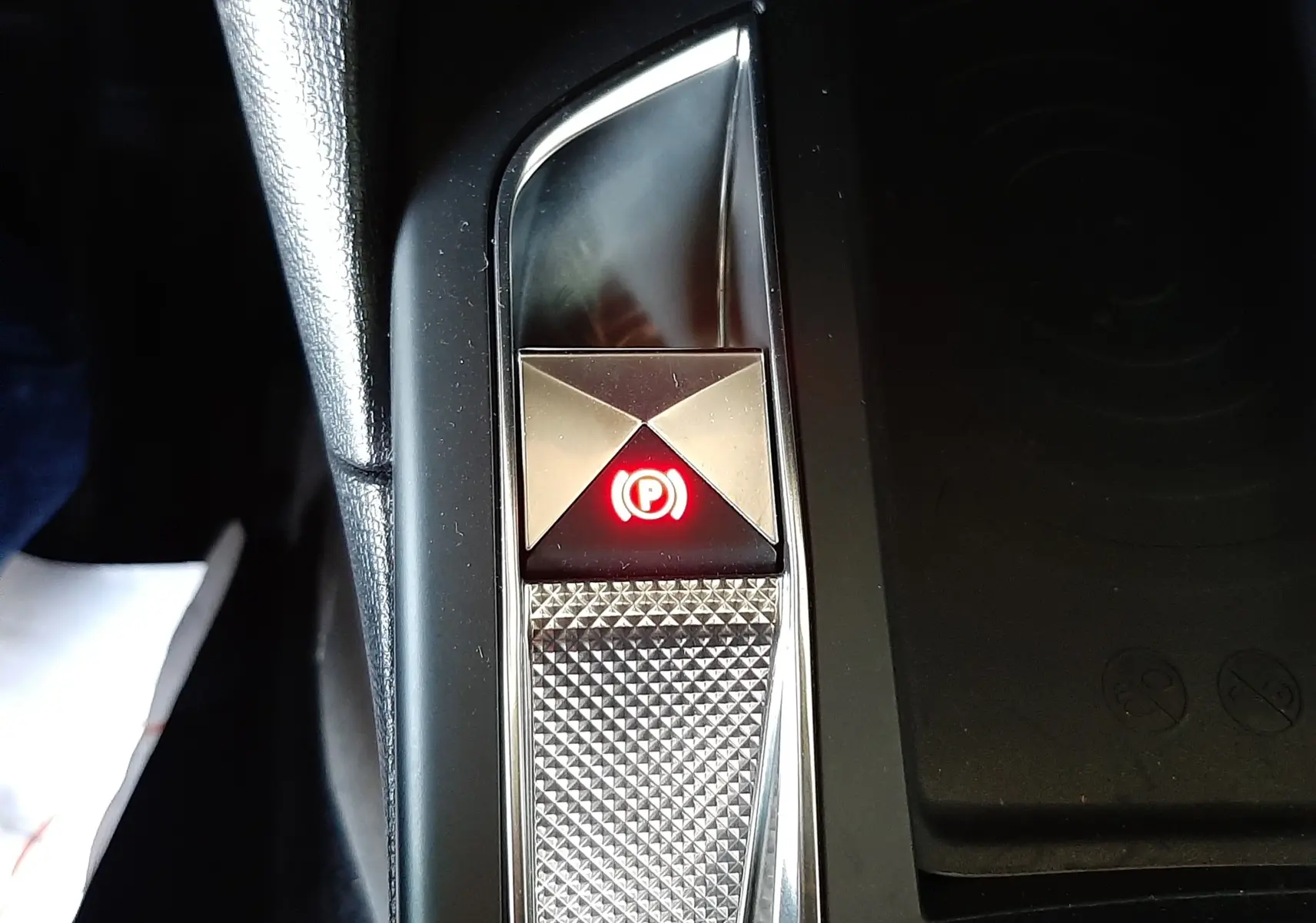 Gros plan sur le bouton de frein à main électronique illuminé en rouge dans l'habitacle du DS3 Crossback gris platinium.