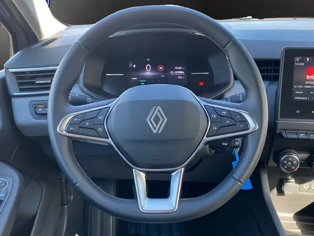 Vue rapprochée du volant textile grainé et du tableau de bord numérique de la Renault Clio V gris Rafale 2025.