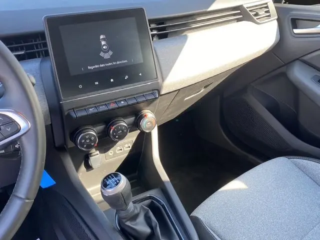 Intérieur avant droit de la Renault Clio V gris Rafale, montrant la console centrale avec écran tactile et levier de vitesse manuel.