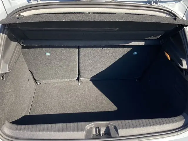 Coffre ouvert vu de l'arrière d'une Renault Clio V gris Rafale, montrant l'espace de chargement et la banquette arrière rabattable.