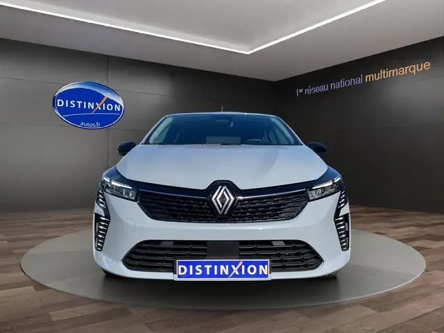 Vue frontale d'une Renault Clio V gris Rafale avec calandre noire et phares Full LED dans un showroom.