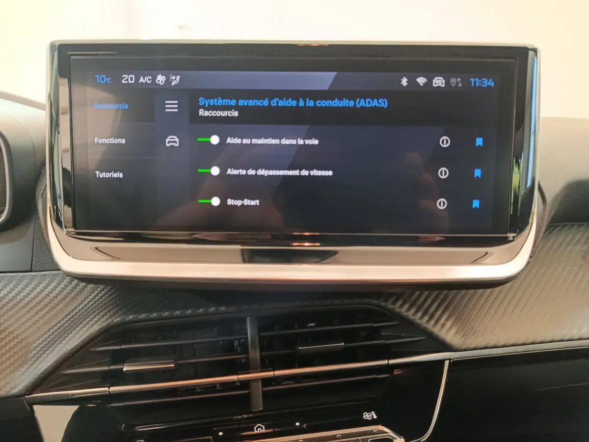 Écran tactile central affichant les aides à la conduite dans l'habitacle d'une Peugeot 208 gris foncé.
