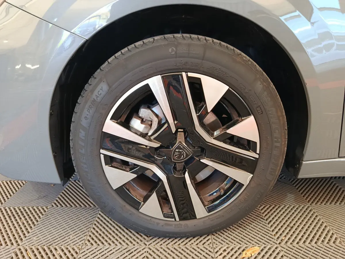 Gros plan sur la roue avant gauche gris foncé de la Peugeot 208 PureTech 100 S&S Allure avec jante noire et argentée.