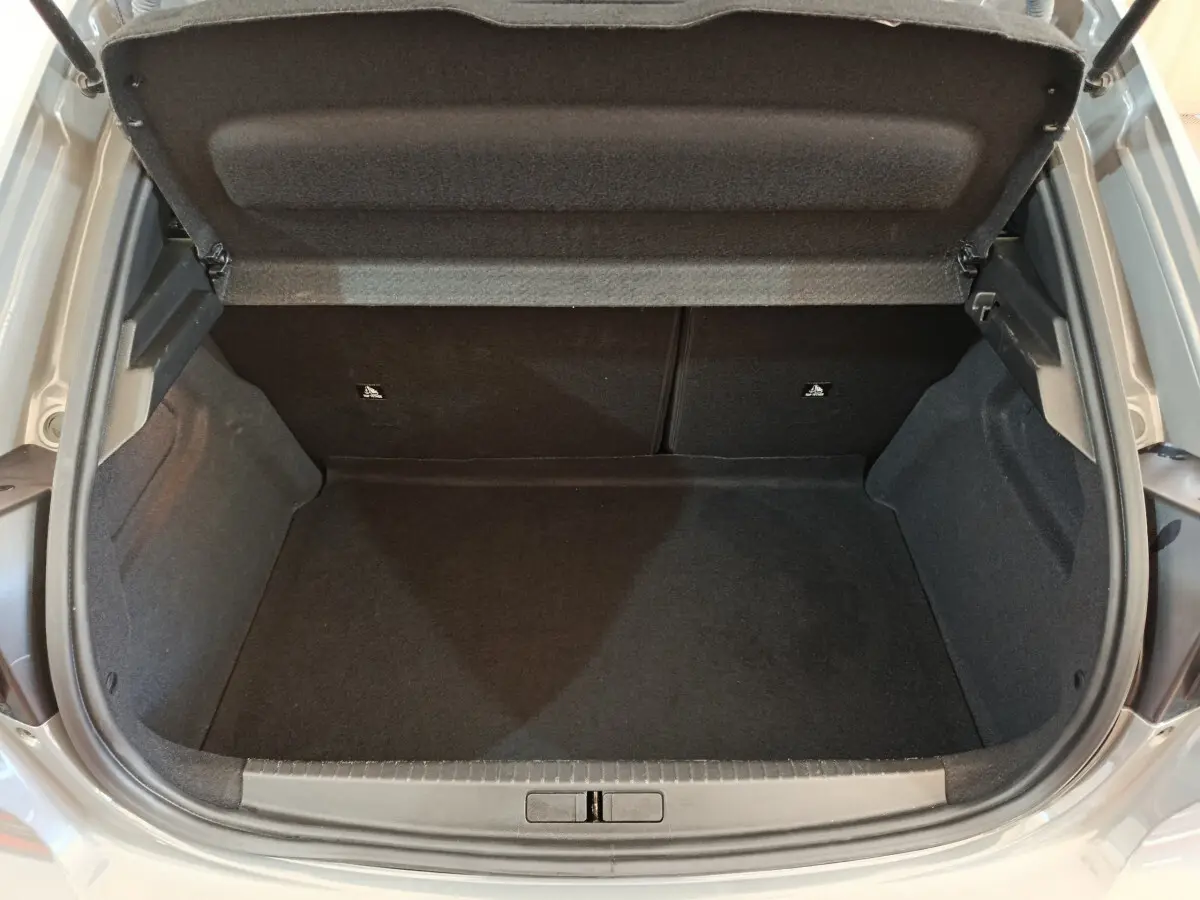 Coffre ouvert vu de dessus d'une Peugeot 208 gris foncé, montrant un espace de chargement propre et spacieux.