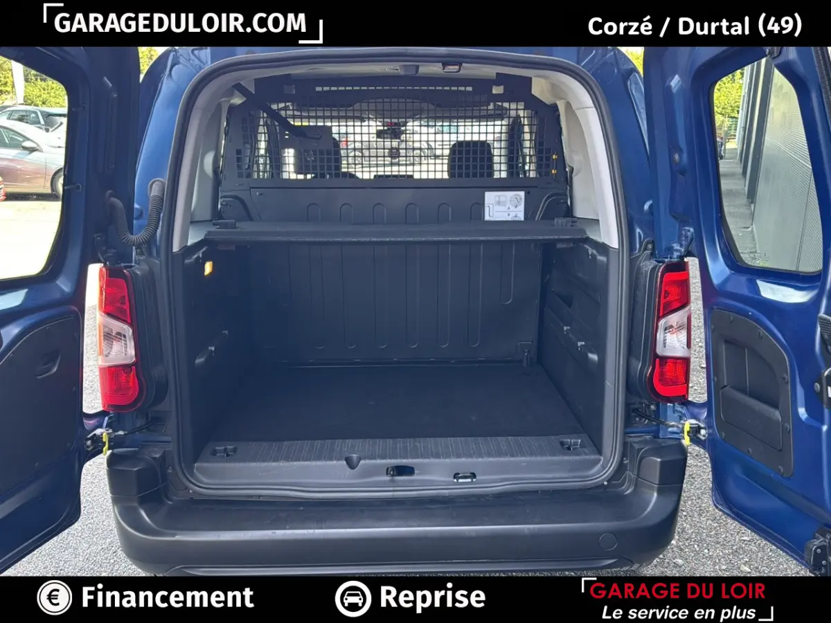 Vue arrière du Peugeot Rifter bleu 2024 avec portes ouvertes montrant le grand espace de chargement vide et la grille de séparation.
