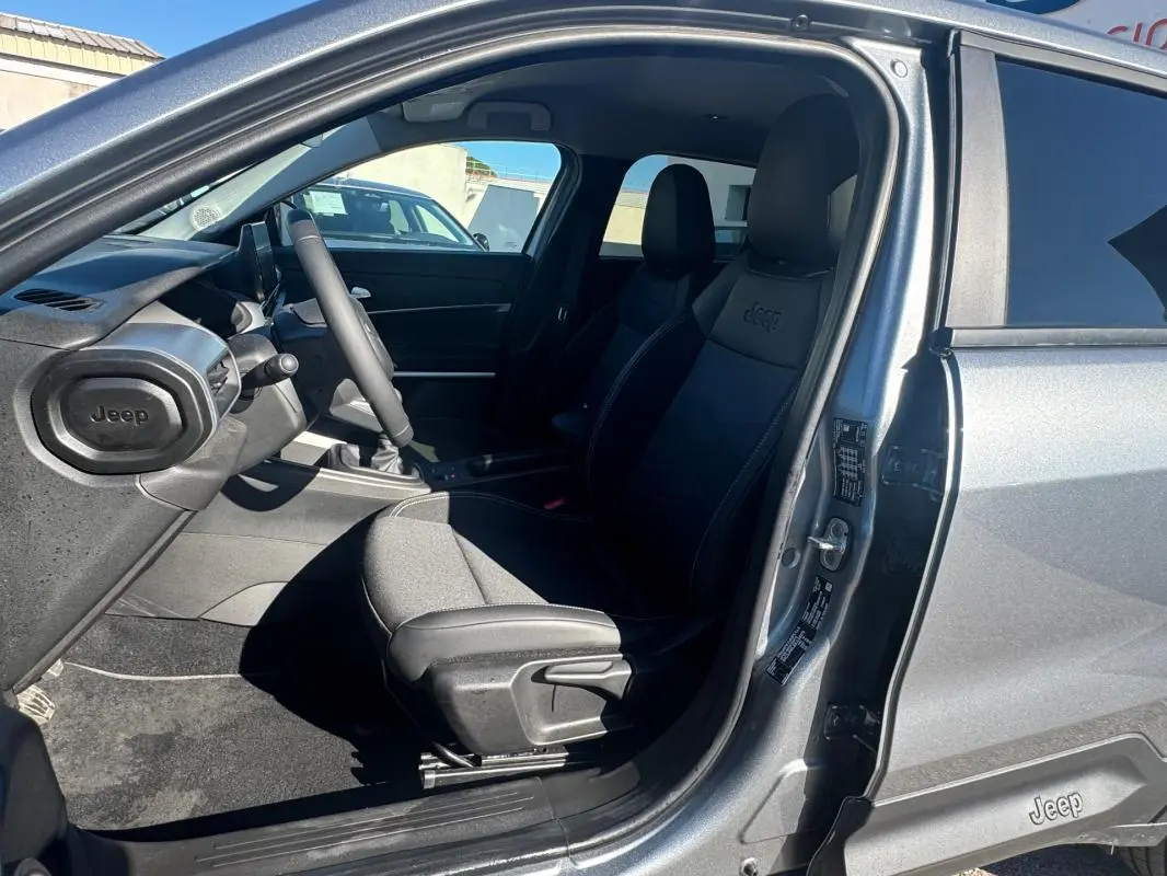 Intérieur côté conducteur du Jeep Avenger gris 2025, montrant siège avant avec logo Jeep et tableau de bord.