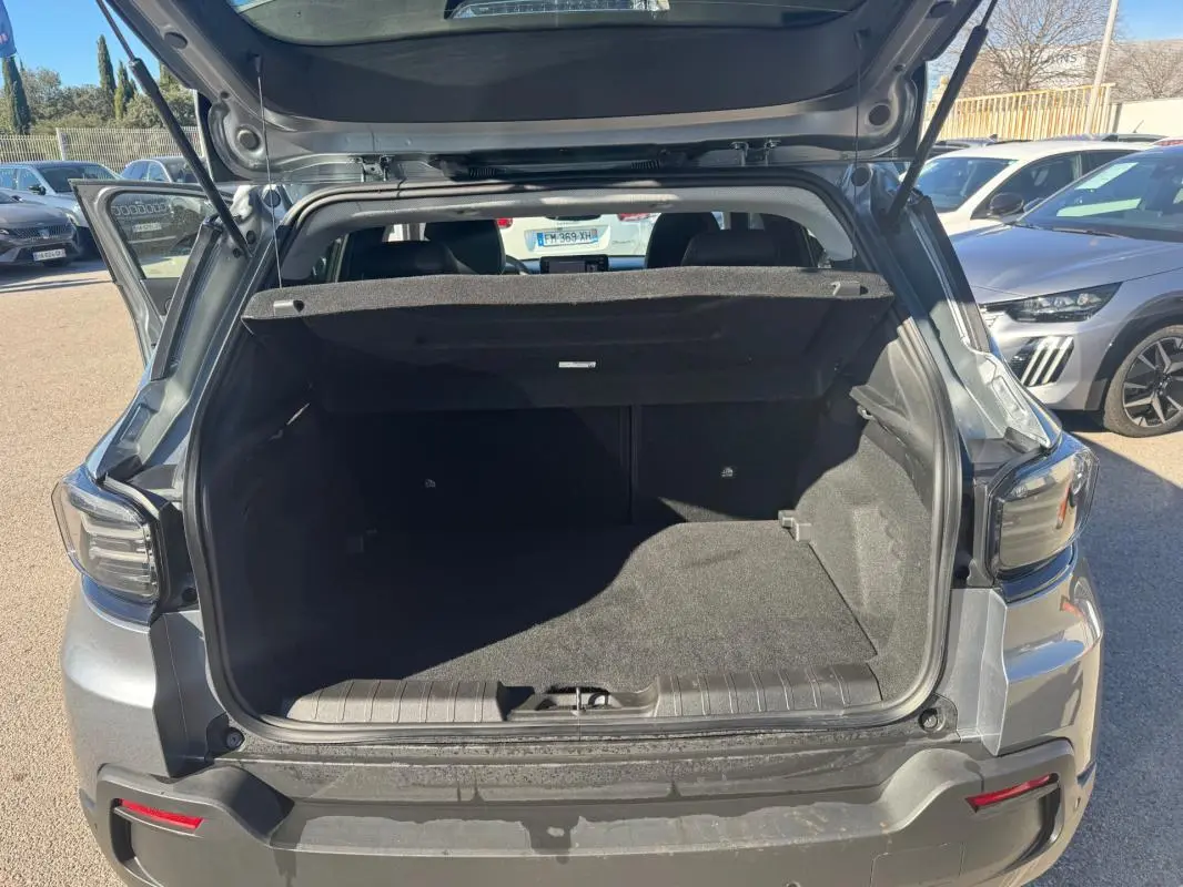 Coffre ouvert vu de l'arrière d'un Jeep Avenger gris 2025, avec hayon relevé et intérieur spacieux.