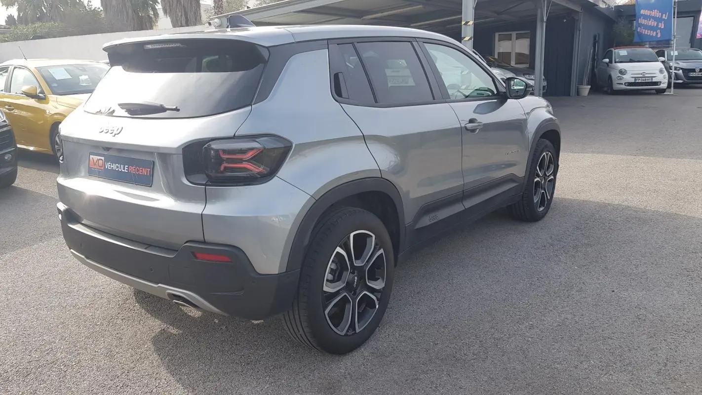 Vue 3/4 arrière droite d’un Jeep Avenger gris avec jantes alliage 18 pouces et feux arrière au design moderne.