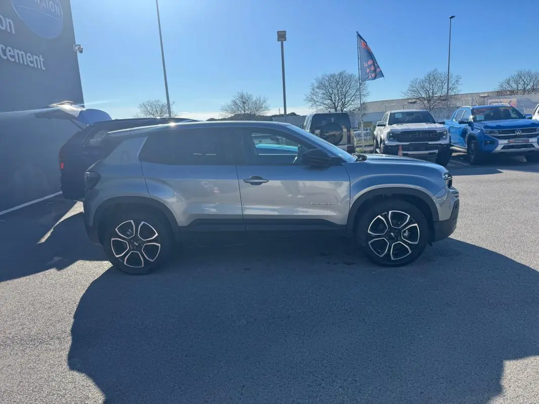 Jeep Avenger gris vu de profil côté gauche, avec jantes alliage noires et détails noirs contrastants.