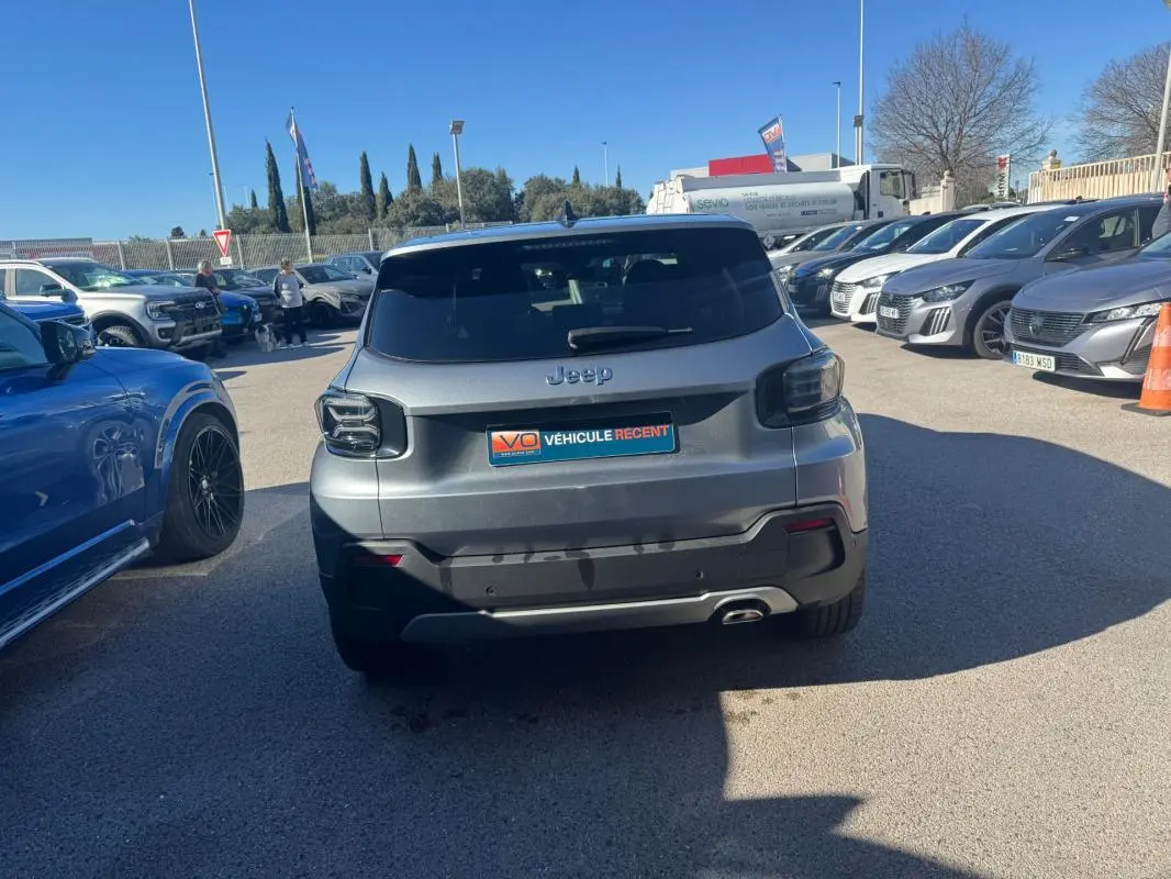 Vue arrière d'un Jeep Avenger gris 2025 avec feux arrière fumés et jantes alliage 18 pouces, stationné en extérieur.
