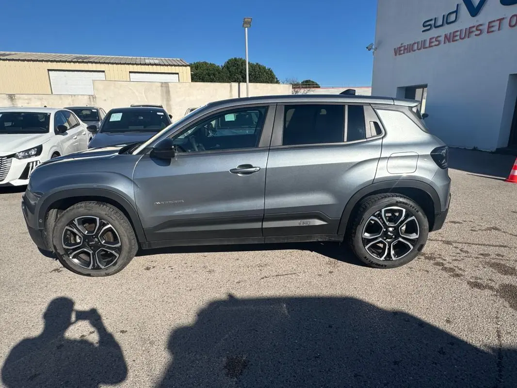 Profil côté gauche d’un Jeep Avenger gris 2025 avec jantes alliage noires et détails noirs sur les ailes.