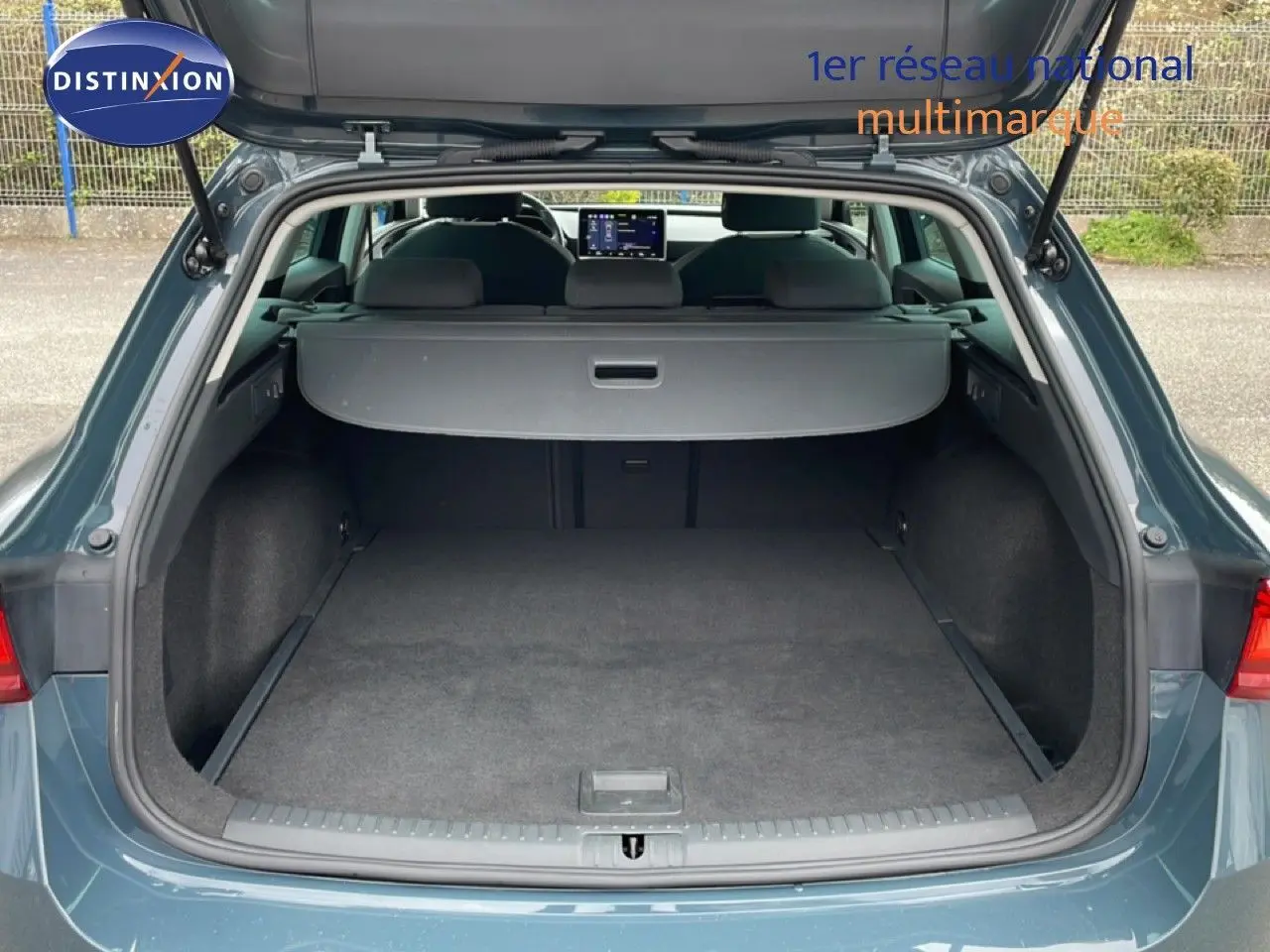 Coffre ouvert vu de l'arrière d'une SEAT LEON ST 2.0 TDI bleu fjord, montrant l'espace de chargement vide et la plage arrière.