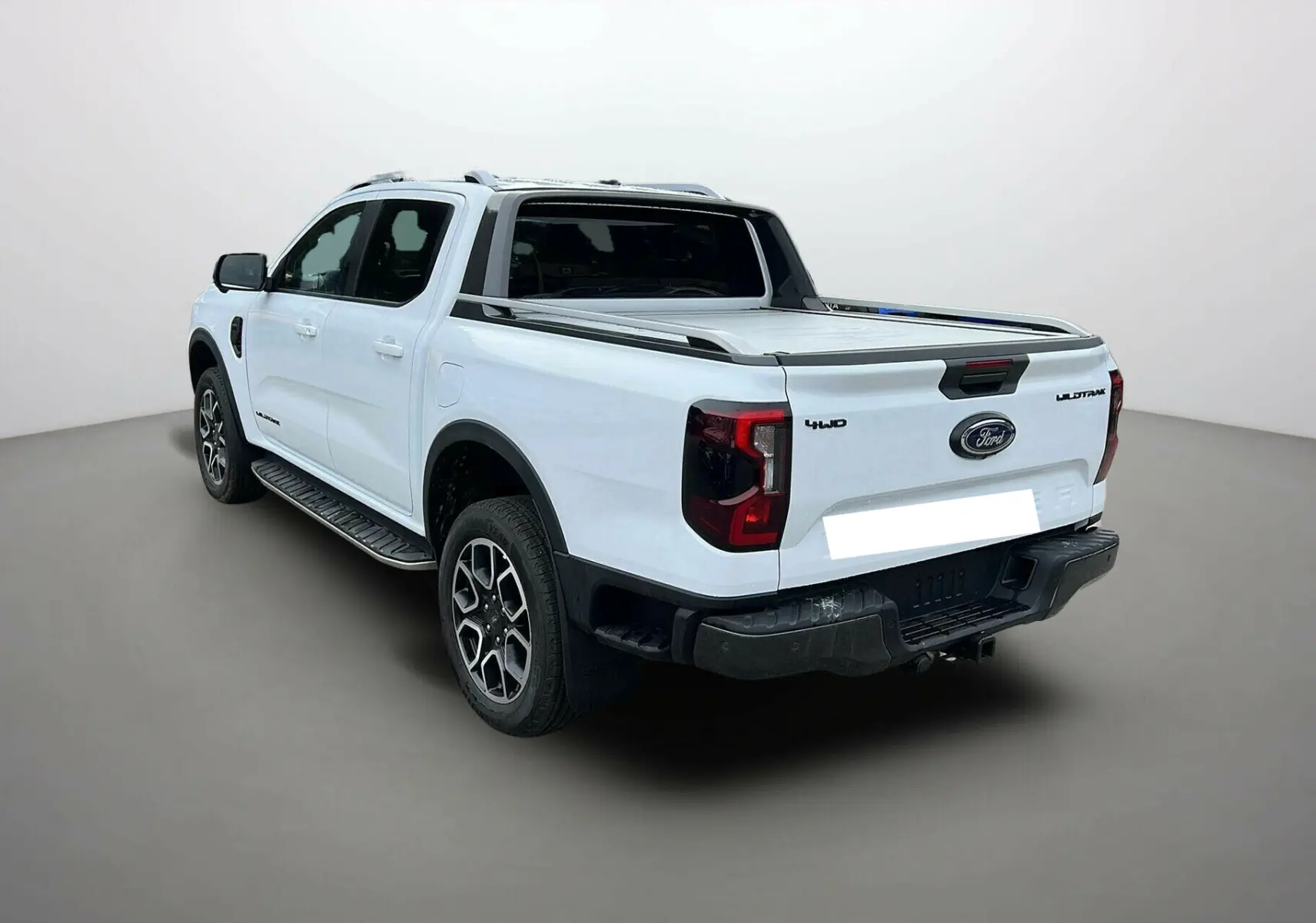 Ford Ranger 2.0 205 Wildtrak Plus blanc glacier, vue 3/4 arrière droit avec benne couverte et jantes alu 20 pouces.