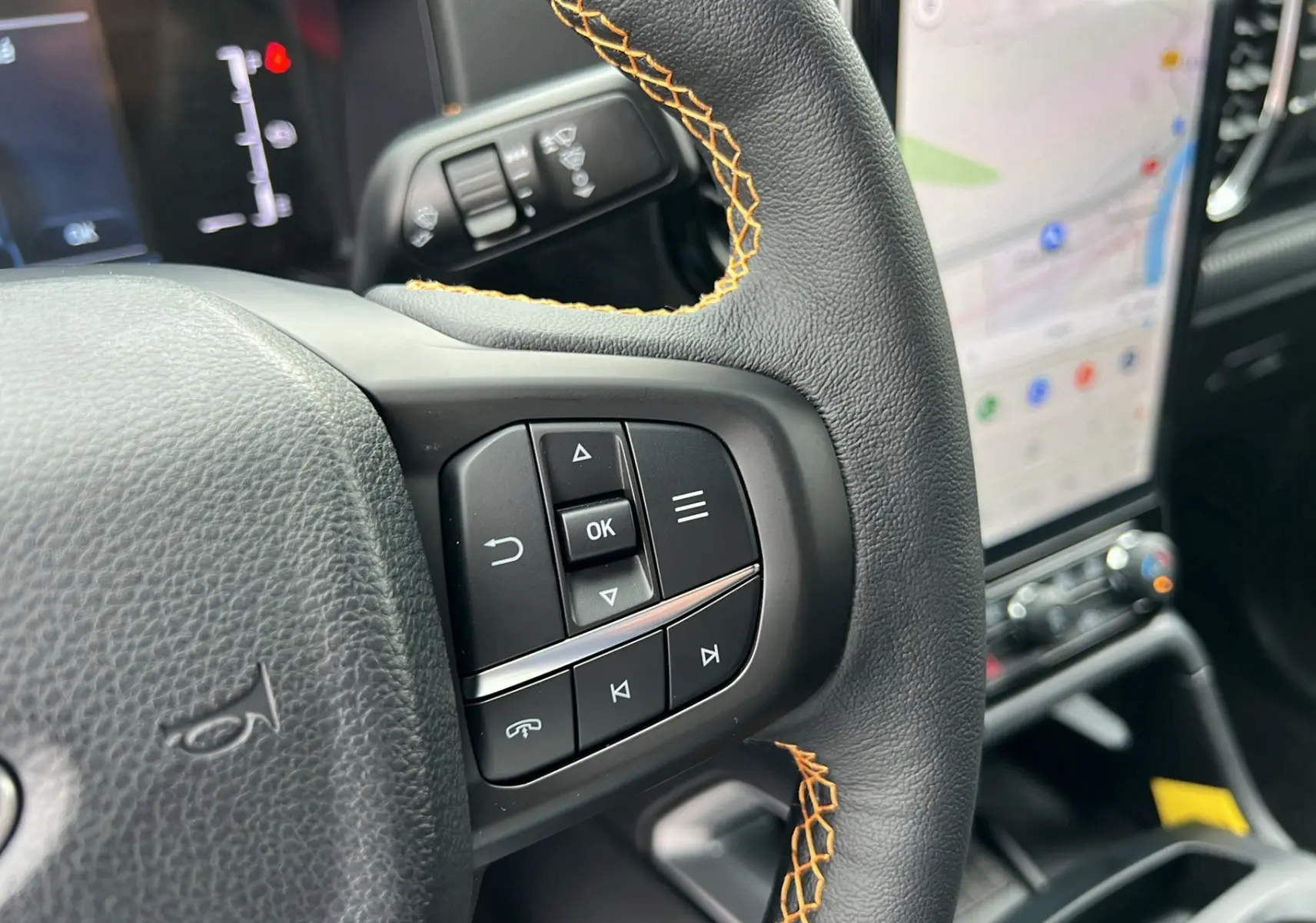Gros plan sur le volant cuir noir avec surpiqûres orange et commandes multifonctions du Ford Ranger 2025.