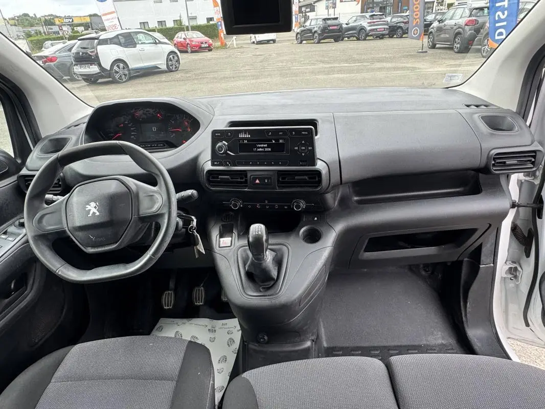 Vue intérieure avant du Peugeot Partner blanc 2020, montrant le volant, tableau de bord et levier de vitesses manuel.