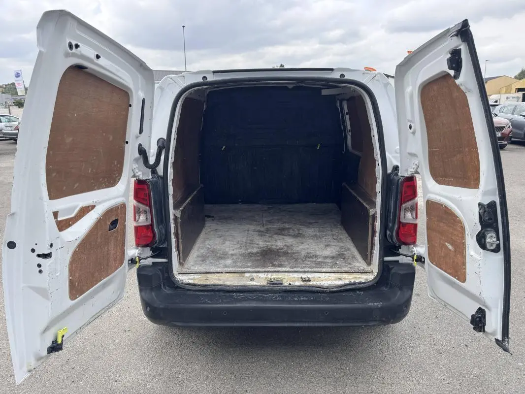 Vue arrière du Peugeot Partner blanc 2020 avec portes ouvertes dévoilant la zone de chargement vide et protégée par des panneaux en bois.
