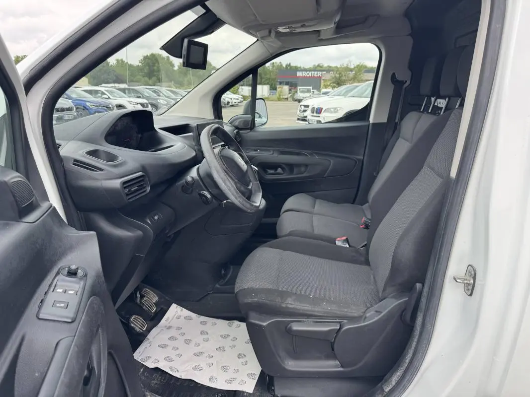 Vue intérieure côté conducteur du Peugeot Partner blanc 2020, montrant le tableau de bord et les sièges avant gris.