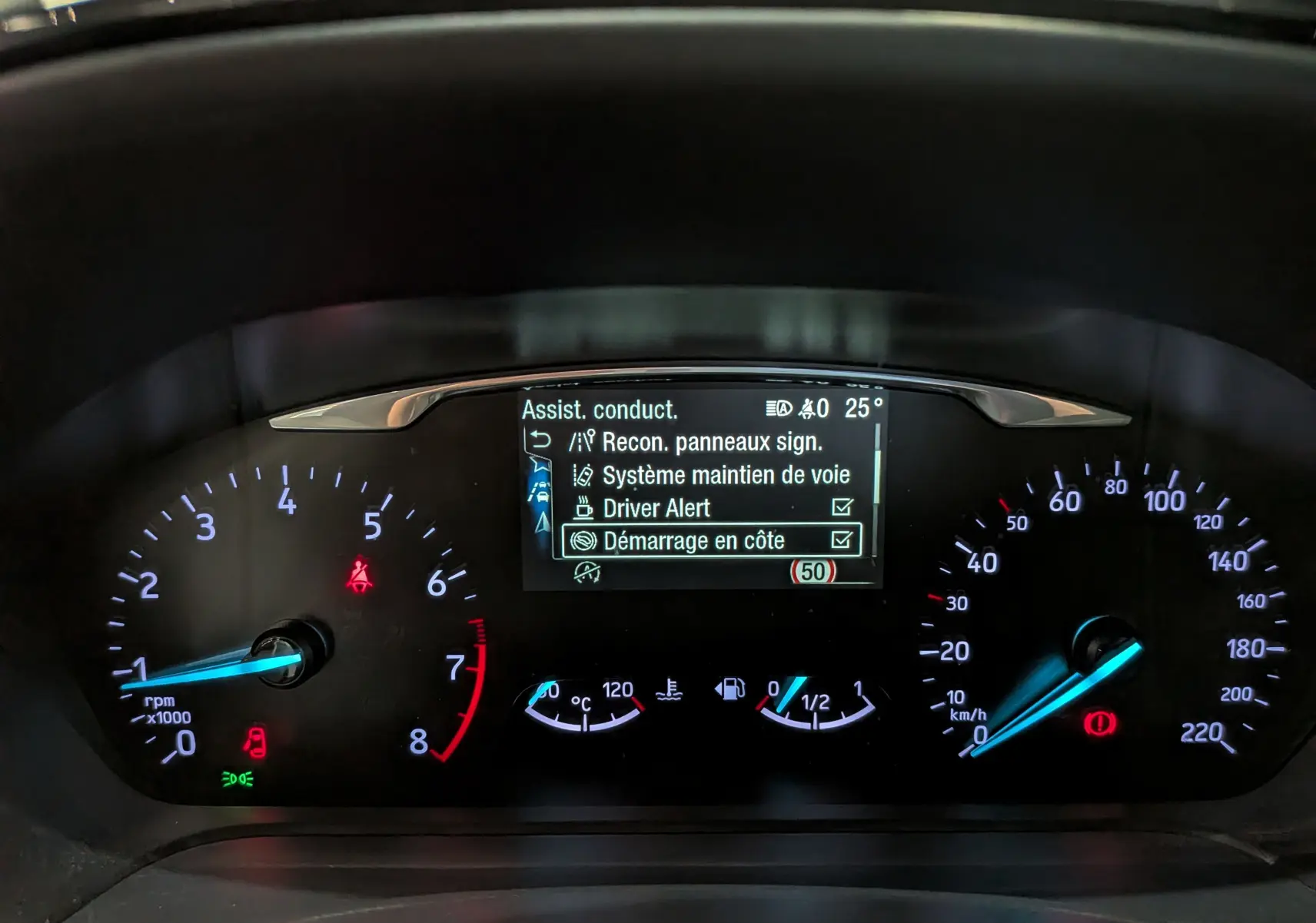 Tableau de bord numérique de Ford Fiesta blanche 2020, affichant les aides à la conduite et compteurs éclairés.