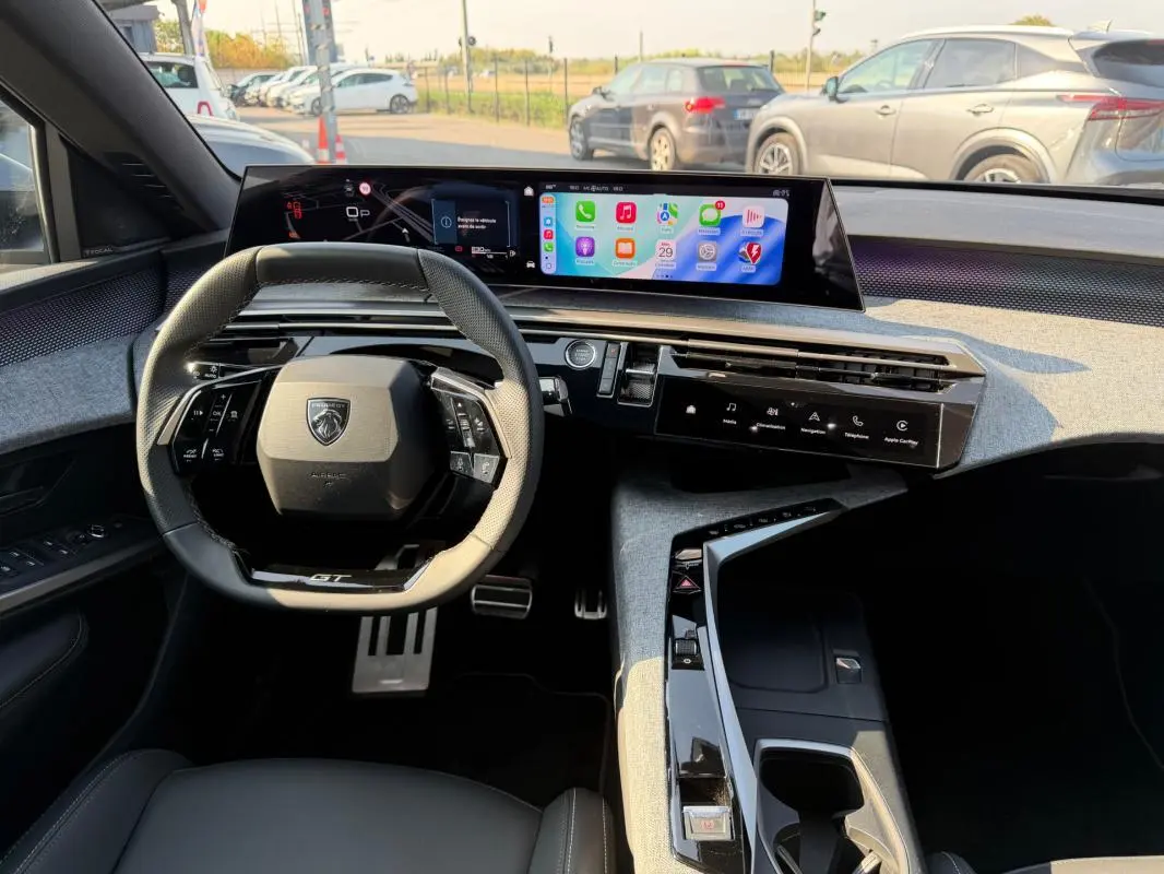 Vue intérieure du tableau de bord du Peugeot 3008 Hybrid GT 2025, avec volant compact et écran numérique panoramique.